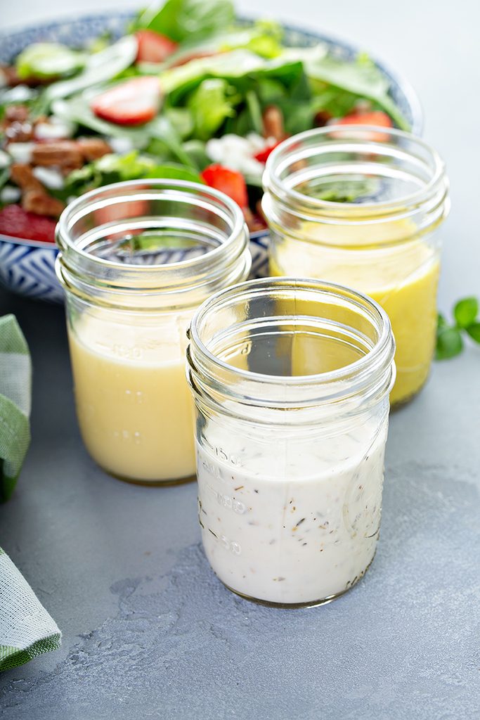 Variety of salad dressings in glass jars with ranch, italian and honey mustard